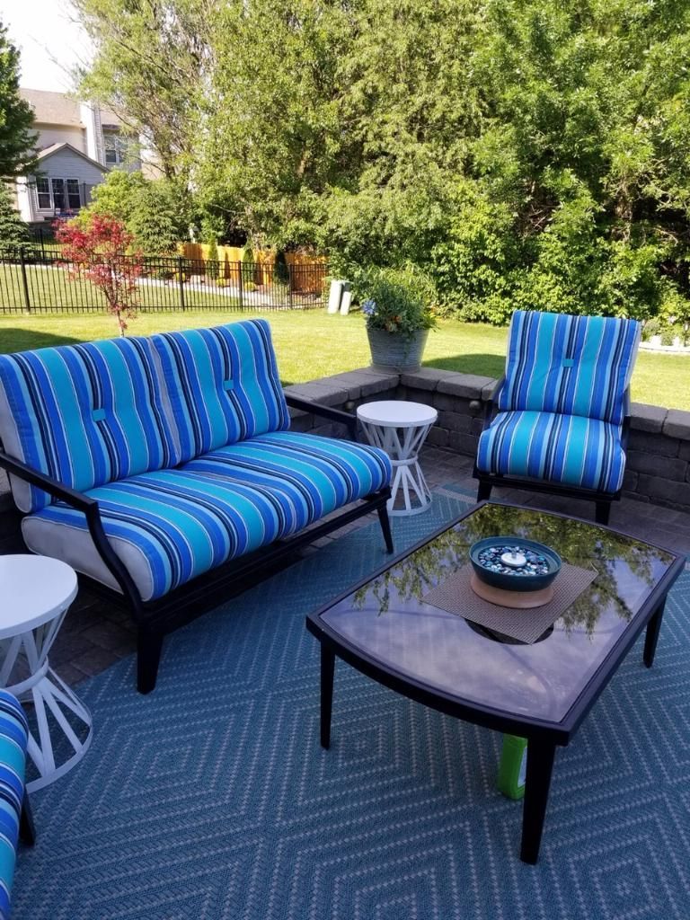 Outdoor patio furniture set with blue and white striped cushions, on a blue patterned rug.
