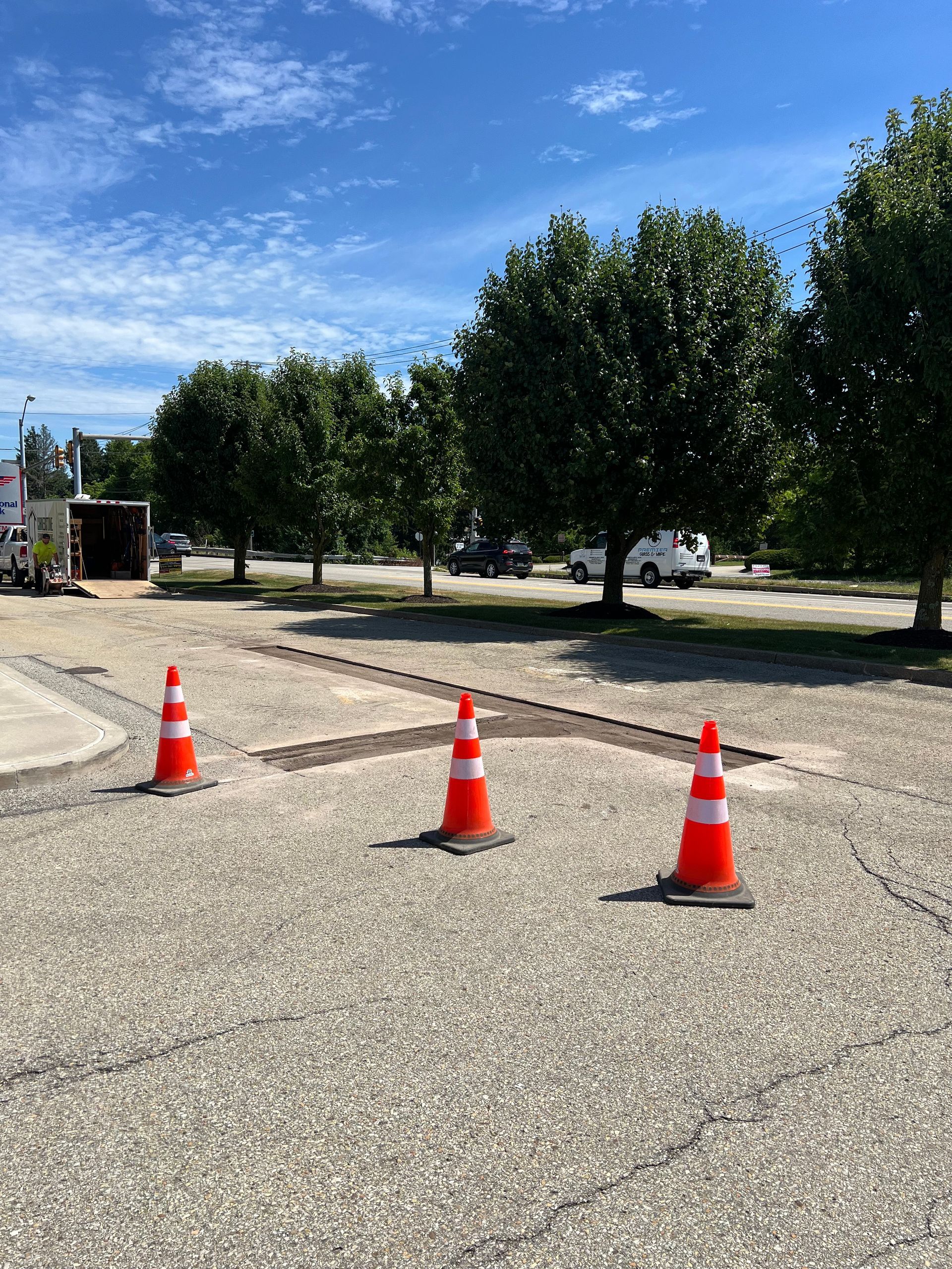 Three orange traffic cones are sitting on the ground in a parking lot.