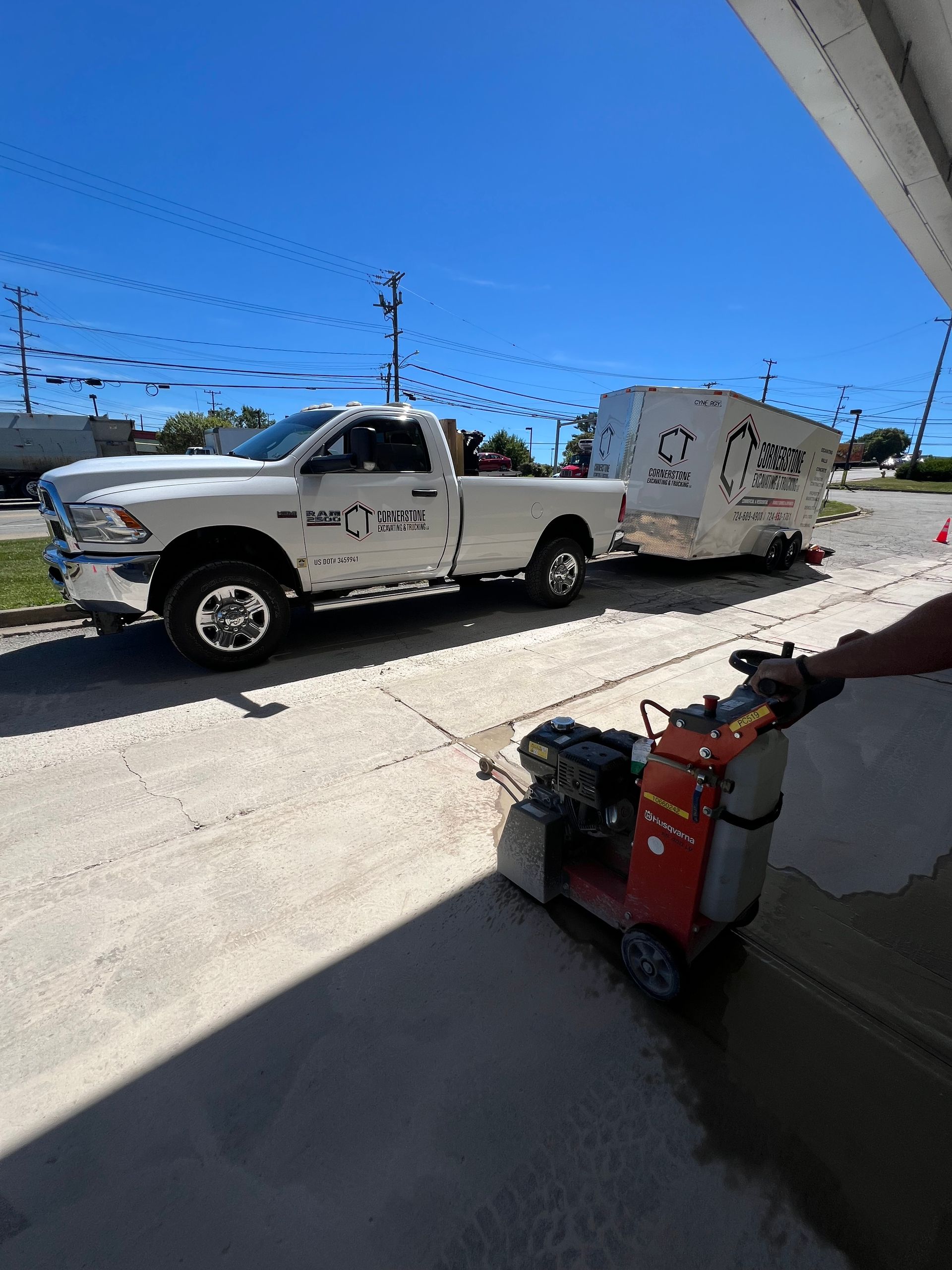 A white truck with a trailer attached to it is parked on the side of the road.