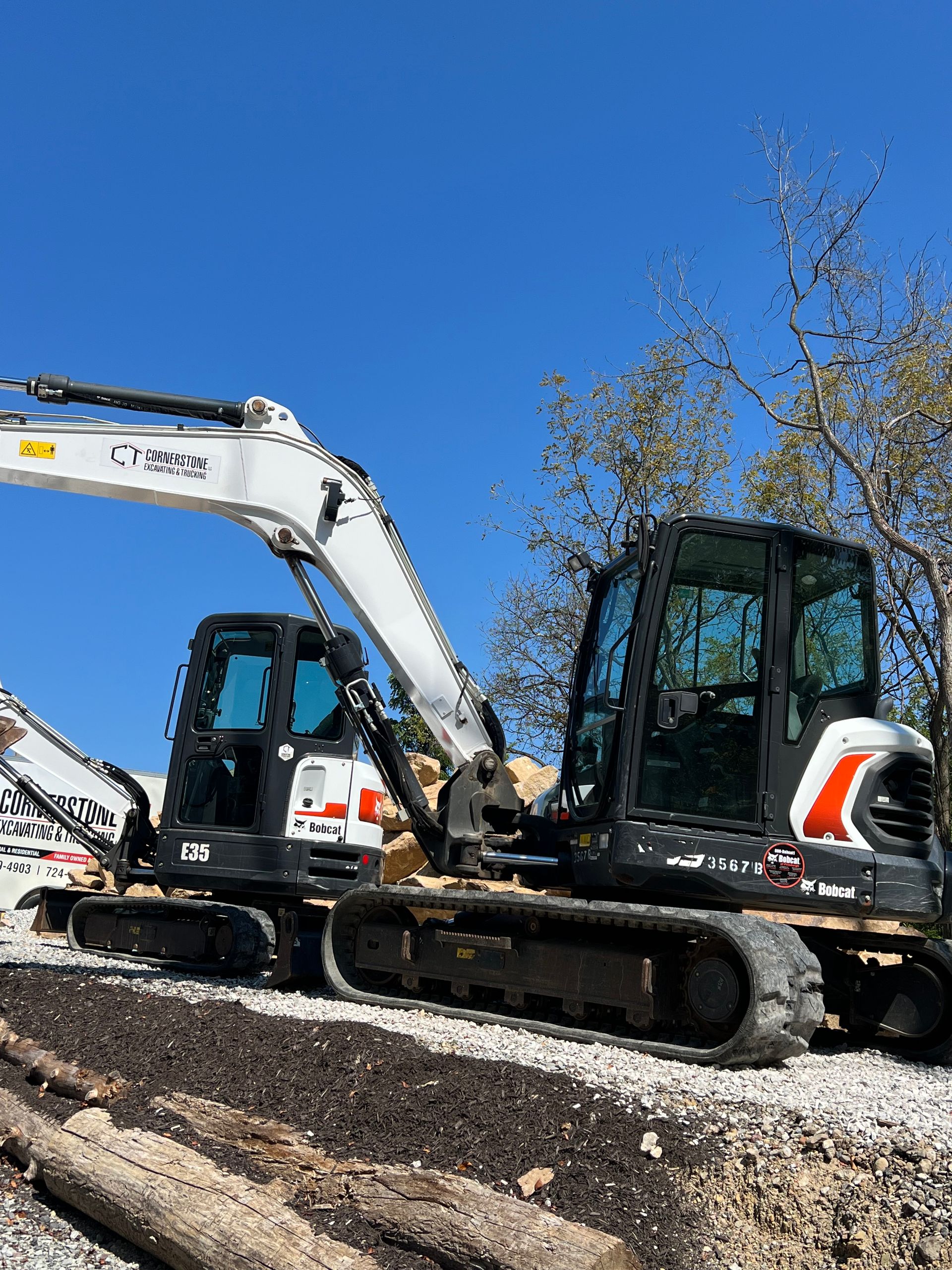 Two excavators are parked next to each other on a dirt road.