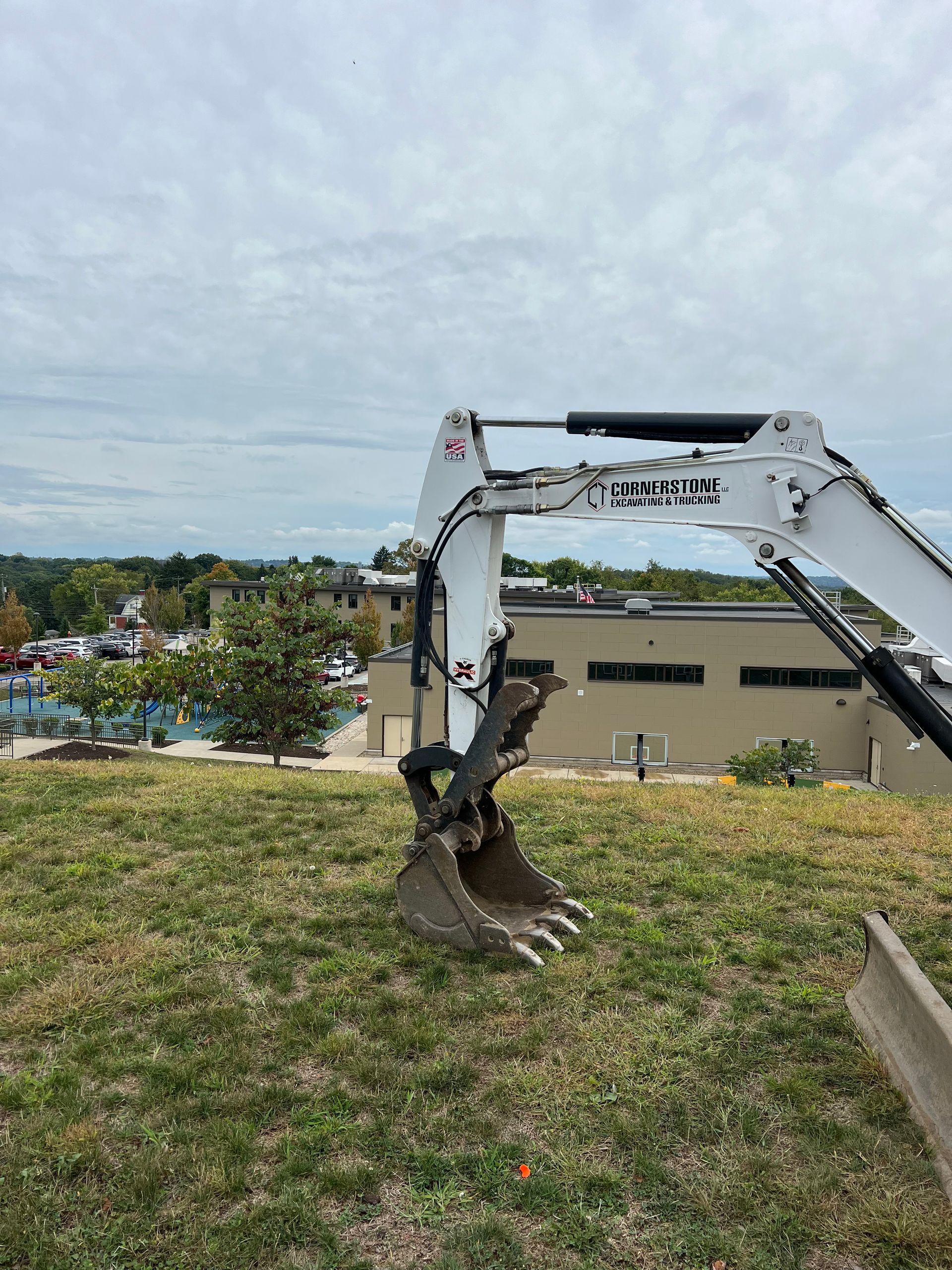 A white excavator is sitting on top of a lush green field.