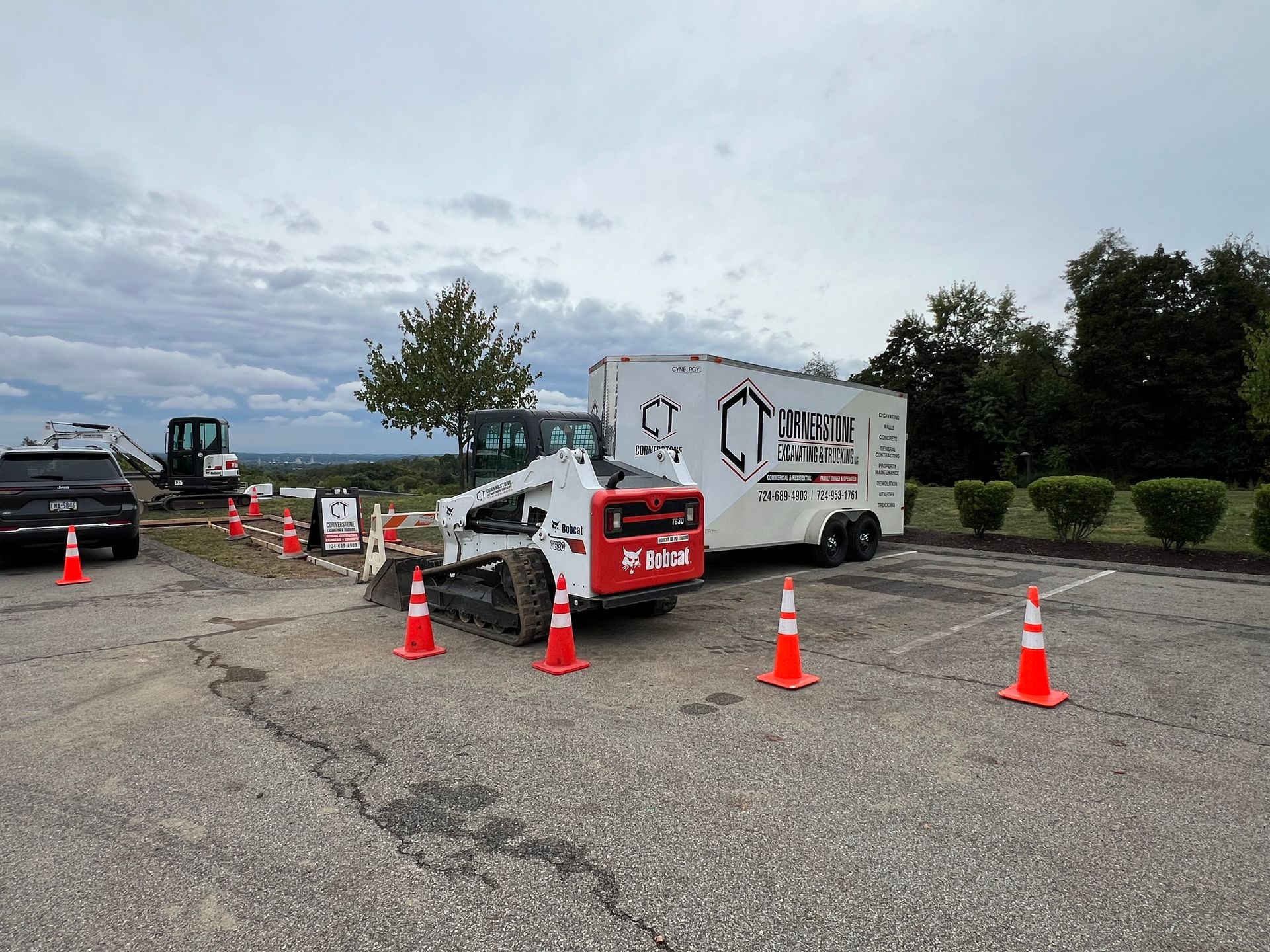 A bulldozer is parked in a parking lot next to a trailer.