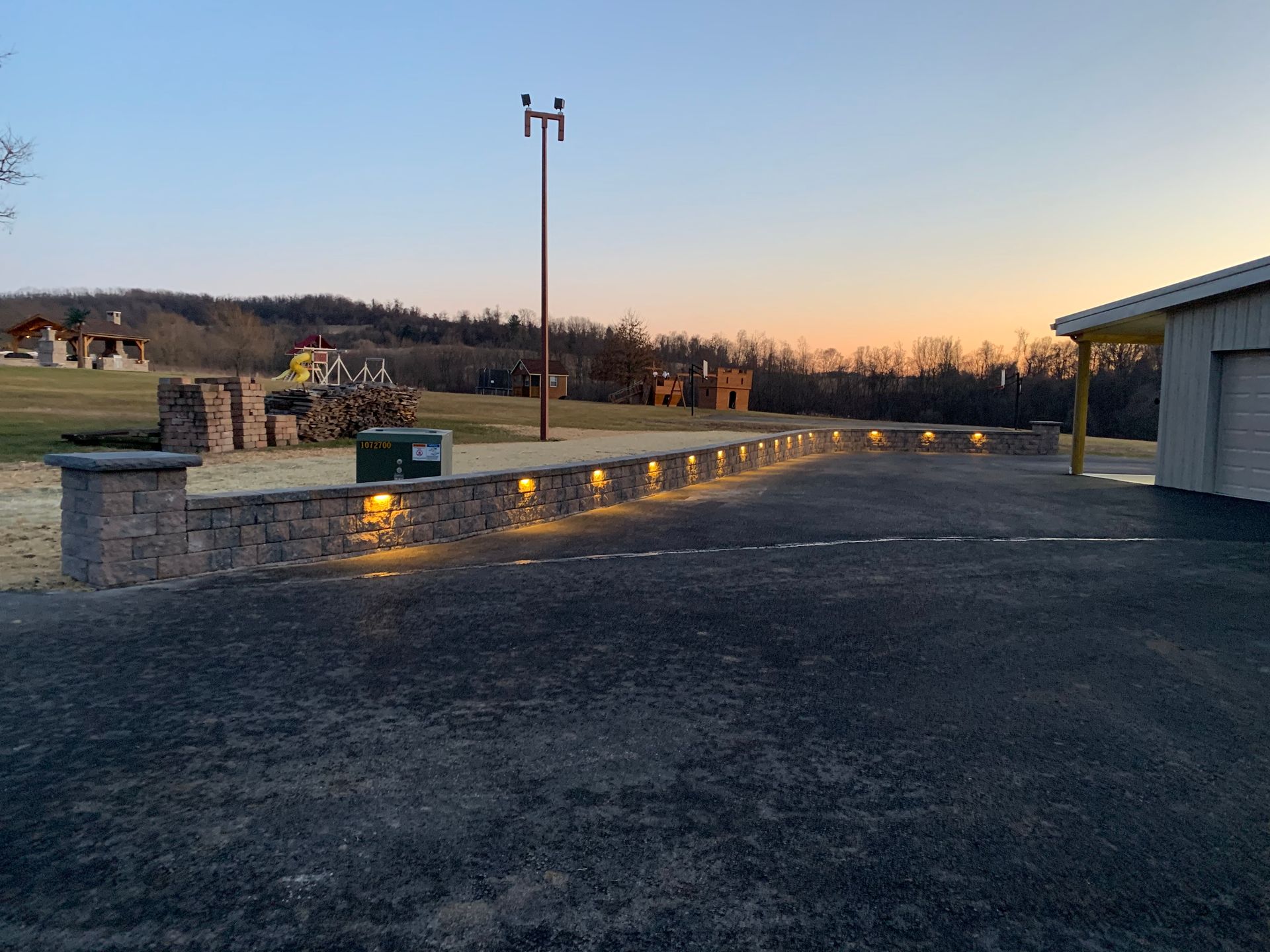 A driveway with a stone wall and lights on it