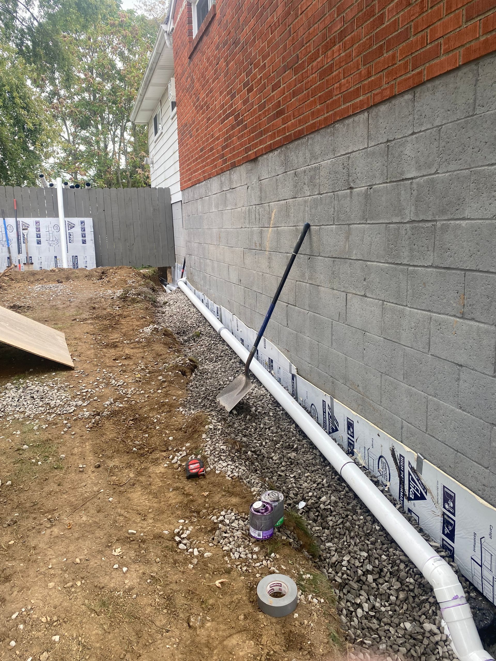 A drain pipe is being installed on the side of a brick building.