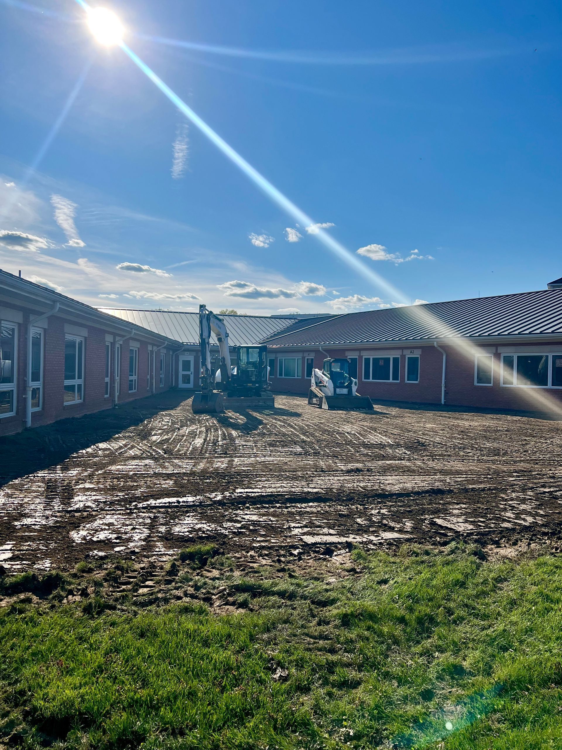 A tractor is moving dirt in front of a brick building