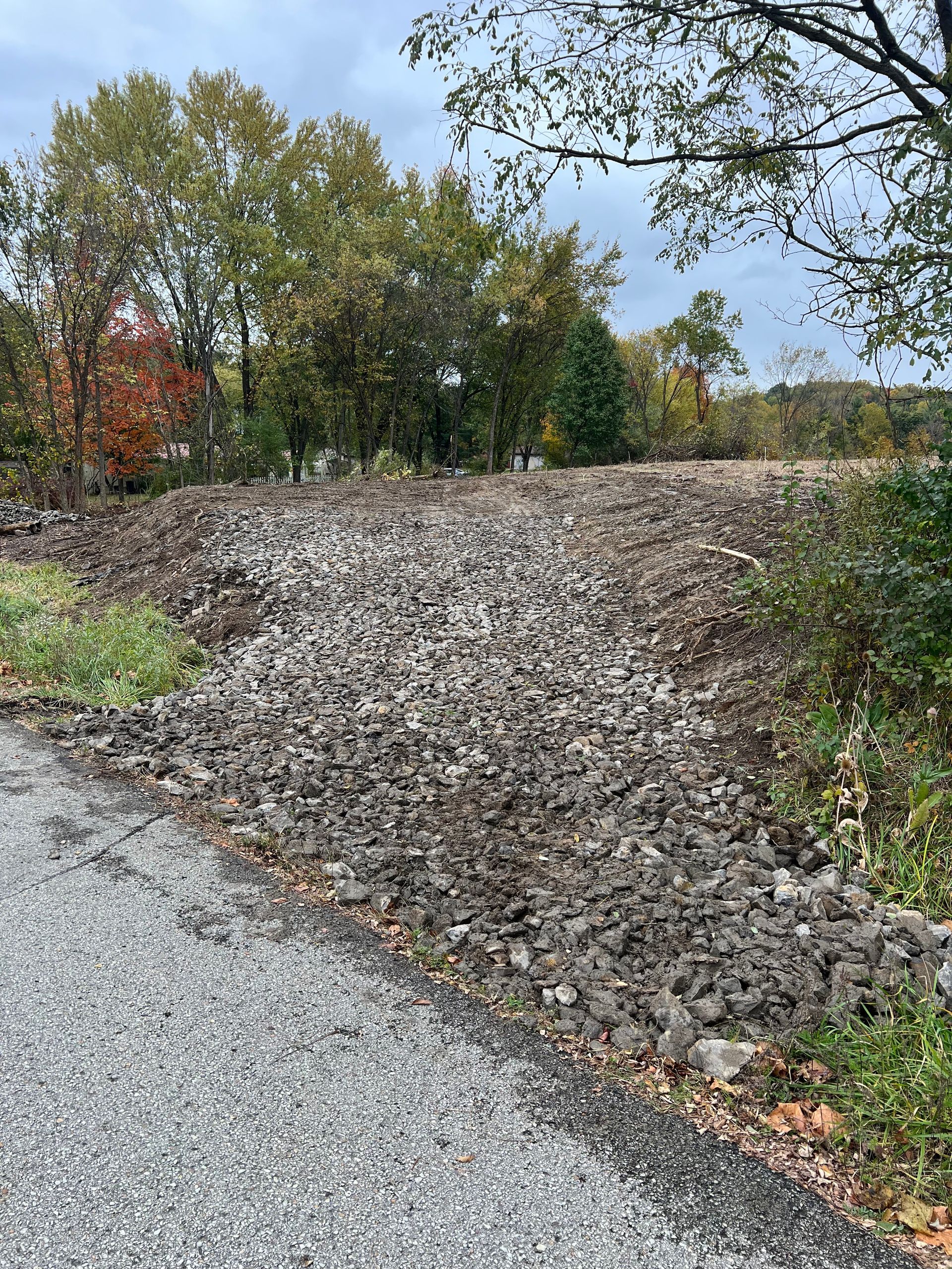 A dirt road with a pile of rocks on the side of it.