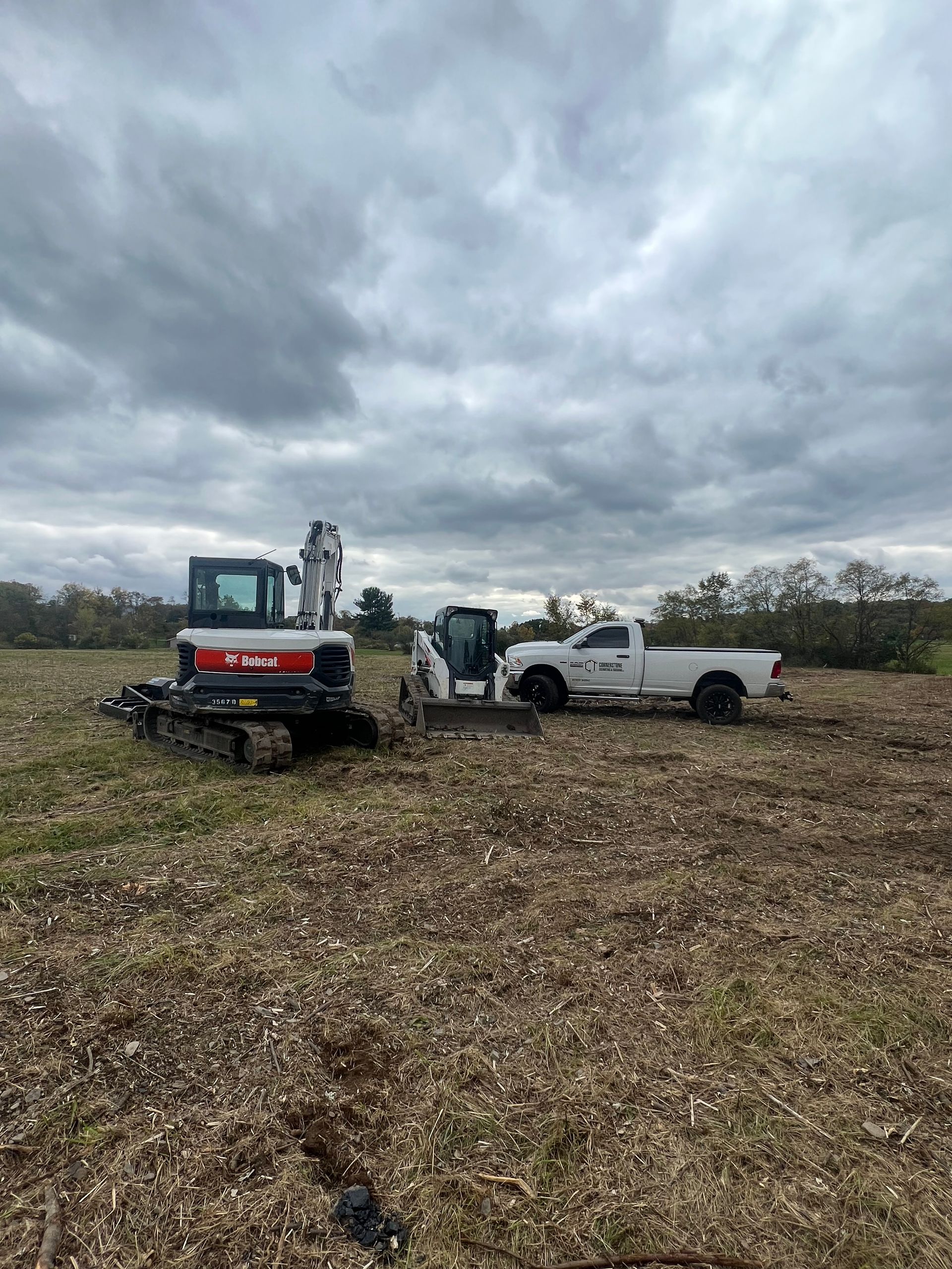 A bulldozer and a truck are parked in a field.