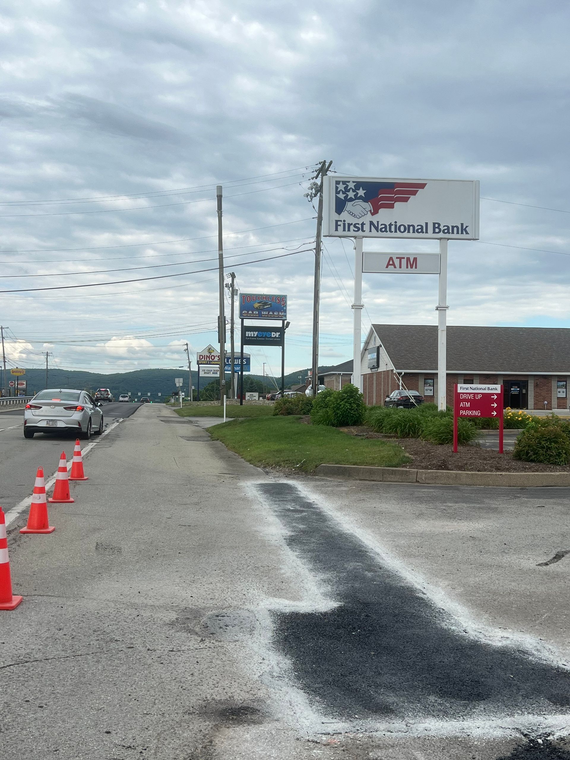 An atm sign is painted on the side of the road