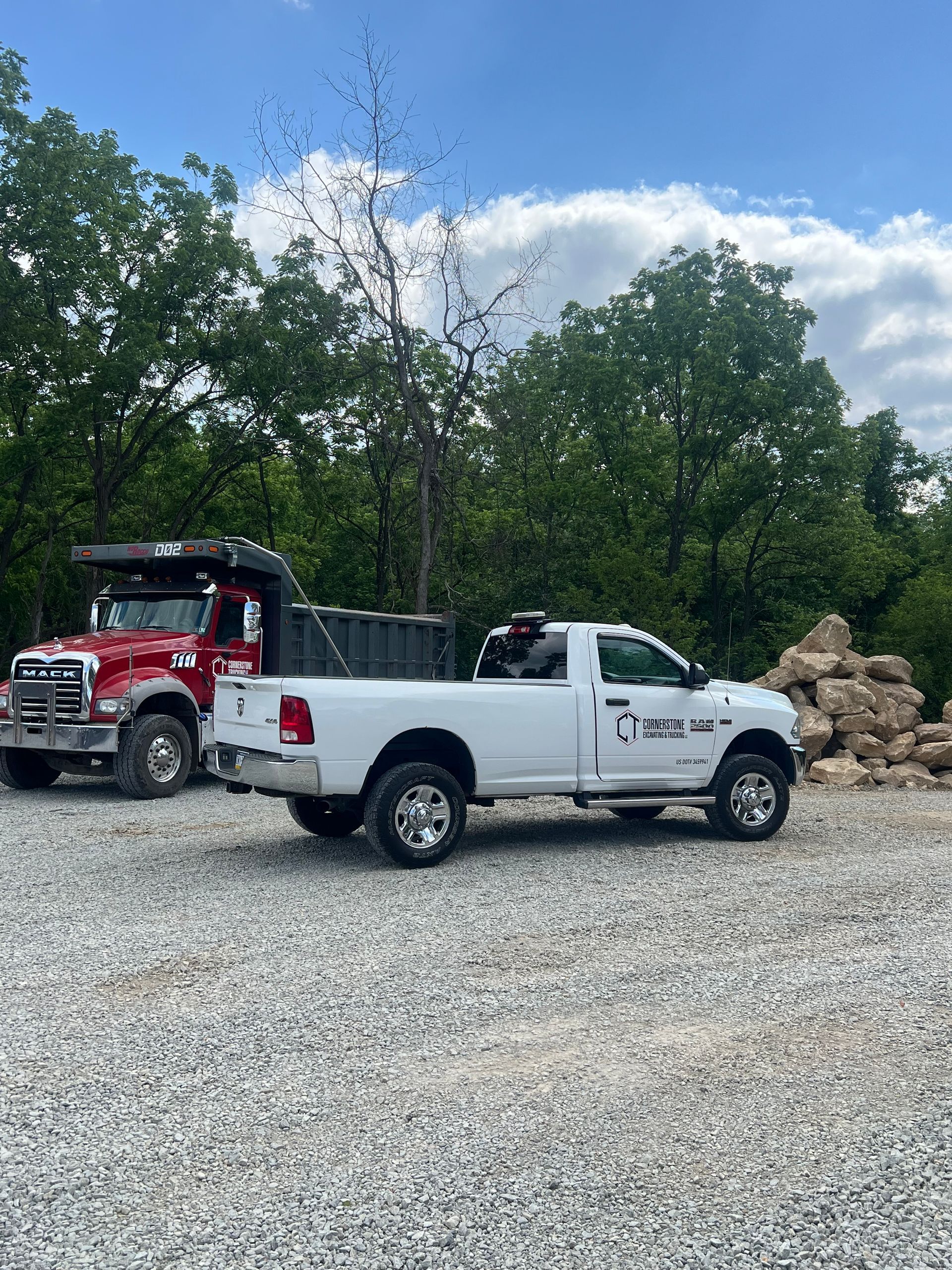 Two trucks are parked next to each other in a gravel lot.