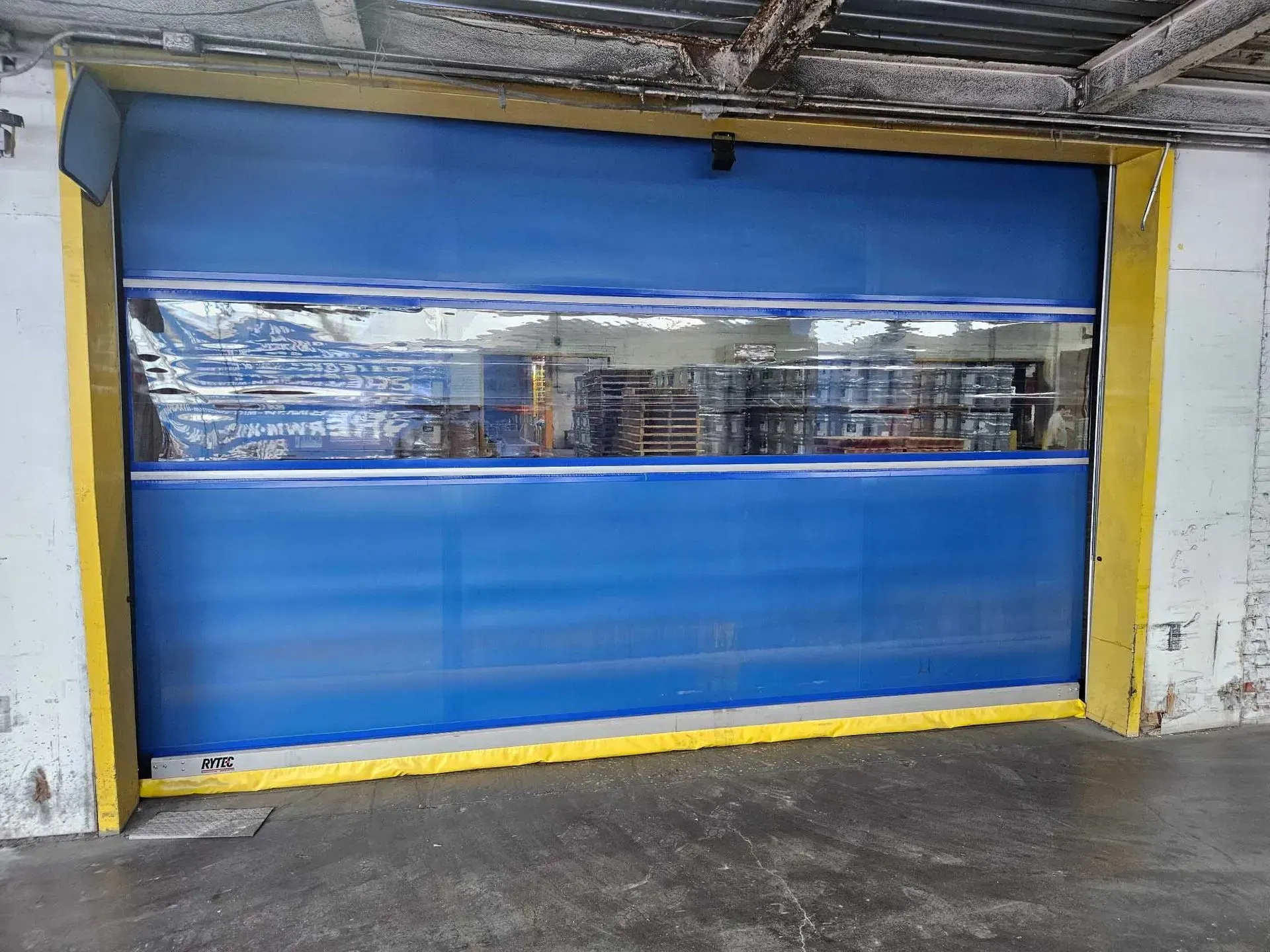 Blue and yellow industrial rapid roll-up door; exterior view.