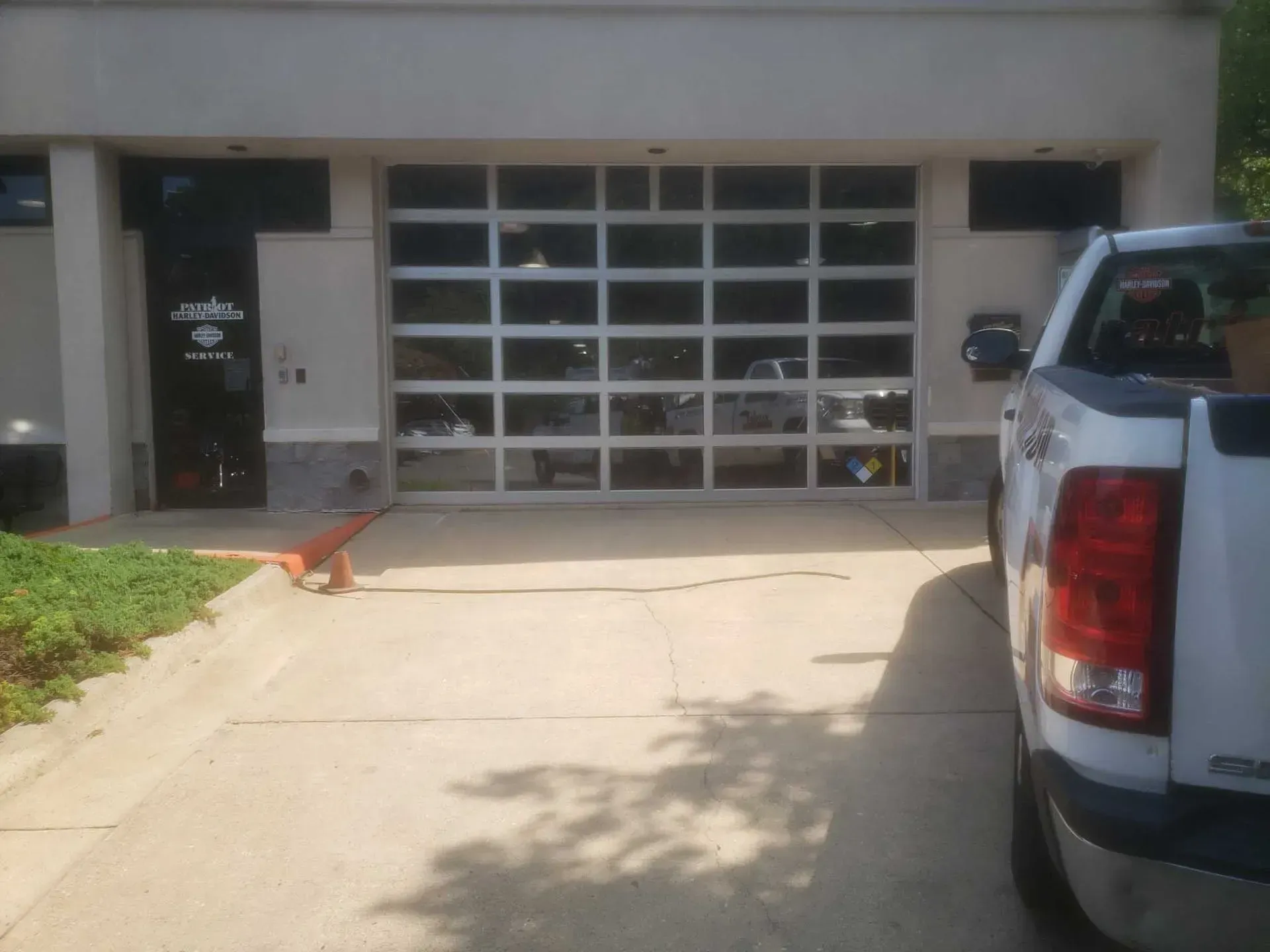 A glass garage door in a white building with a parked pickup truck in front.