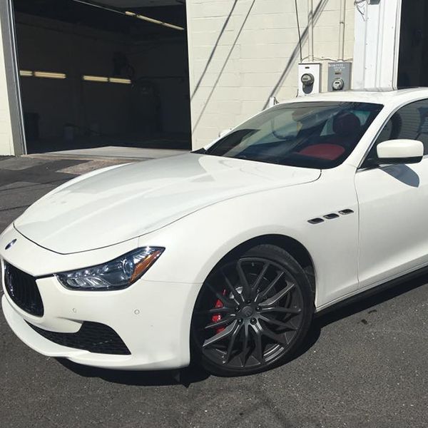 White Maserati Ghibli parked outside, black rims, red brake calipers.