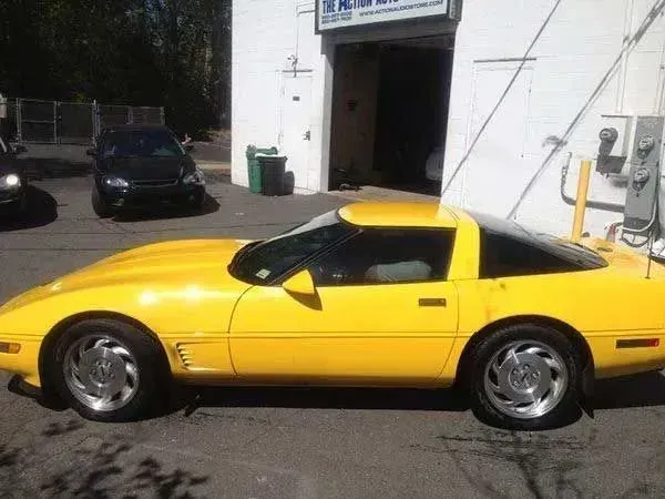 Yellow Corvette parked outside an auto repair shop.