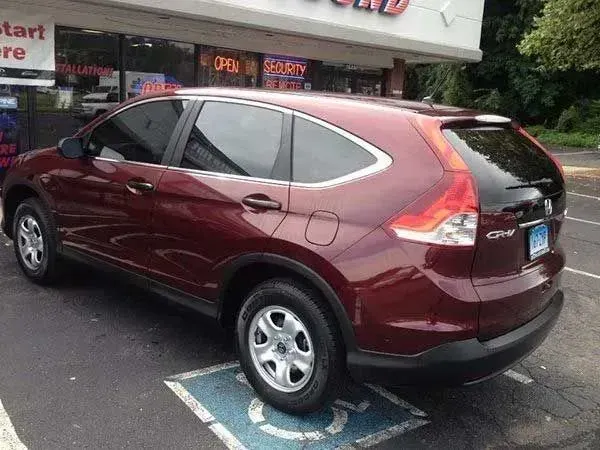 Red Honda CR-V parked in a handicapped spot. Next to a storefront with open sign.