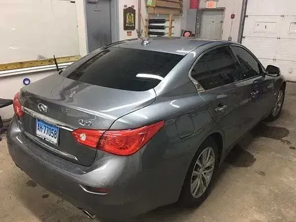 Gray Infiniti Q50 with tinted windows in a garage.