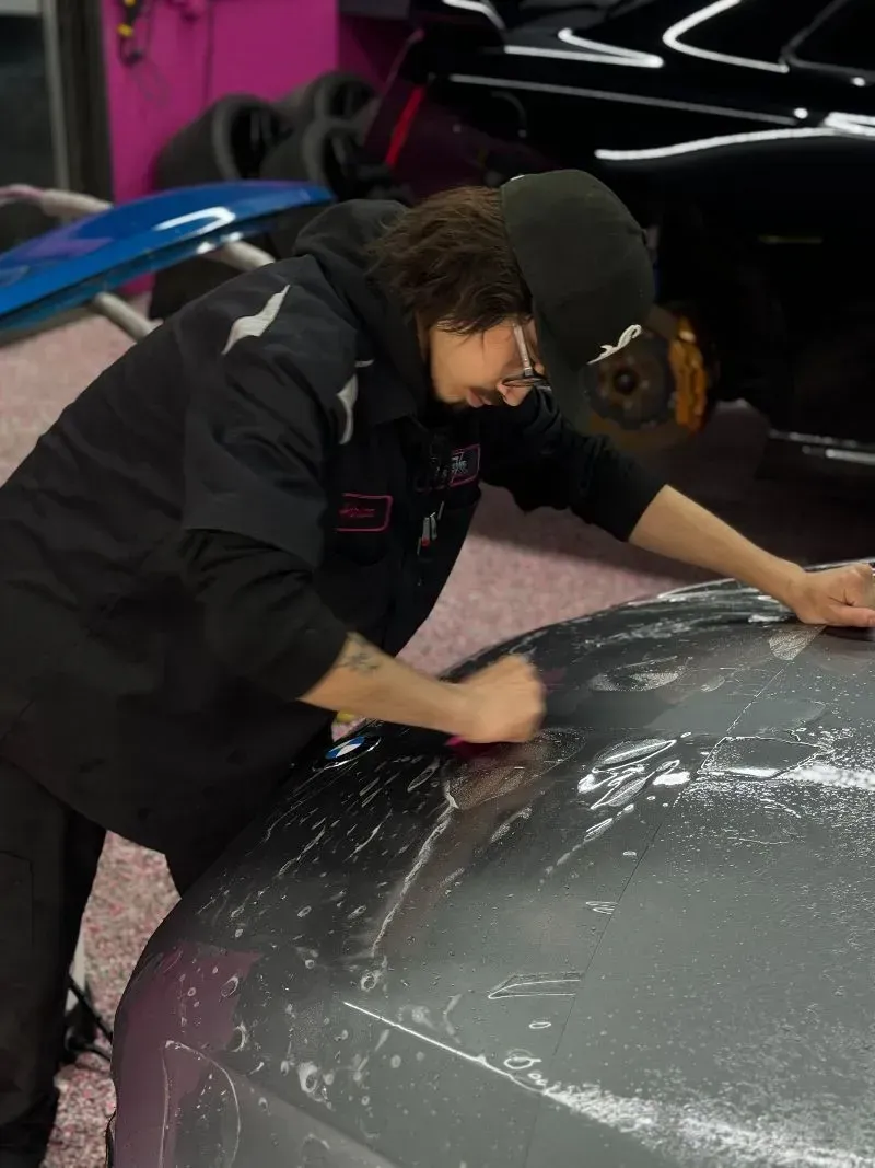 A man is working on the hood of a car