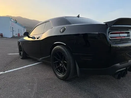 A black dodge challenger is parked in a parking lot.
