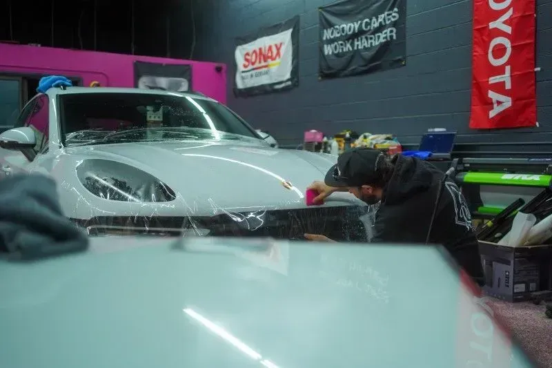 A man is washing a white car in a garage.