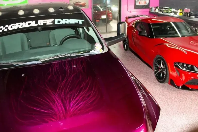 A purple car with a gridlife drift sticker on the windshield