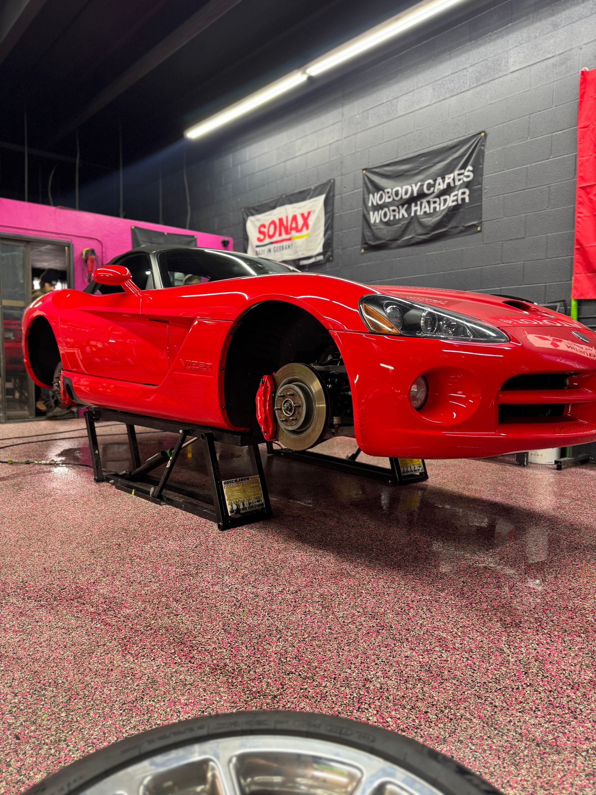 A red dodge viper is sitting on a lift in a garage.