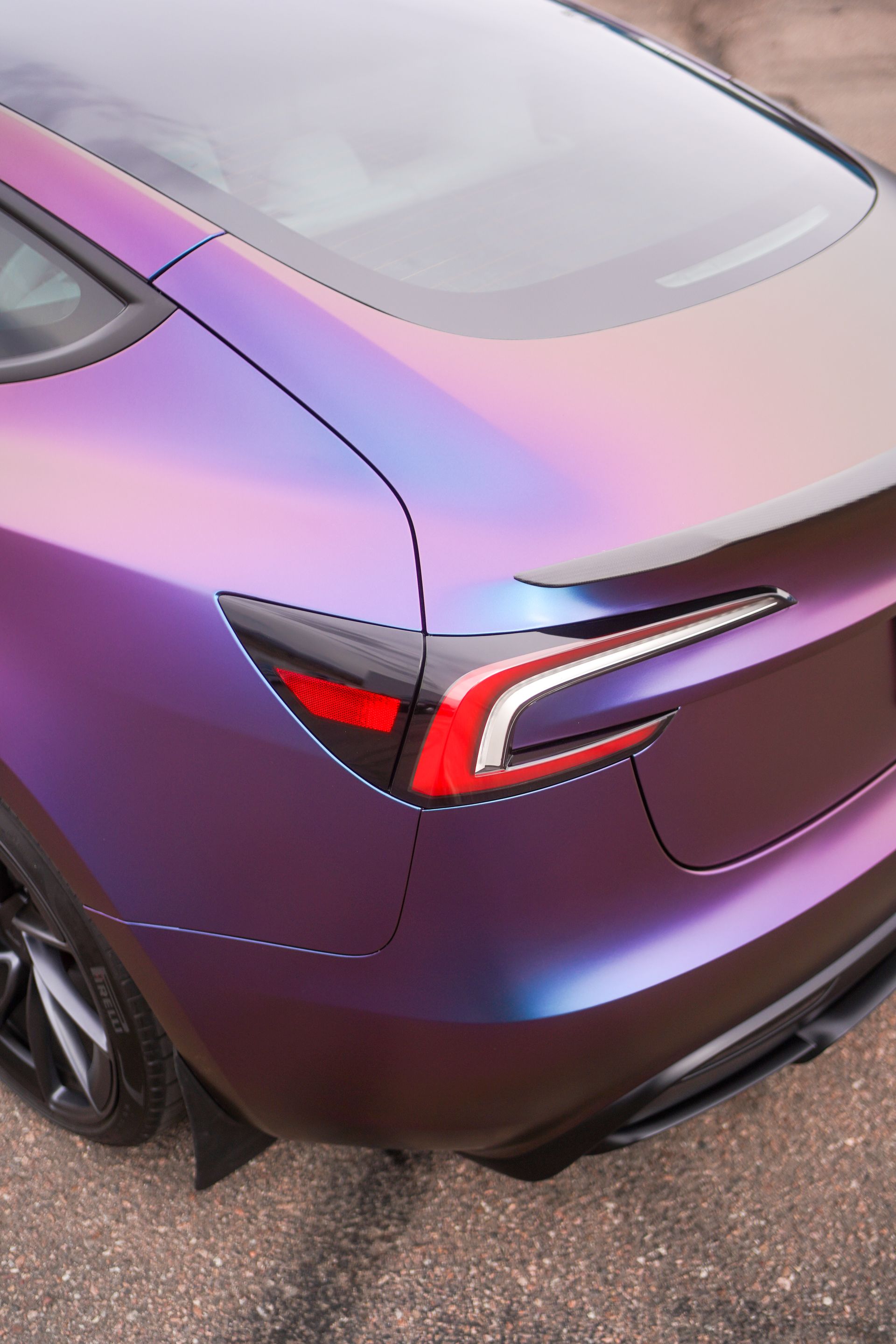 The rear end of a purple tesla model 3 is shown.