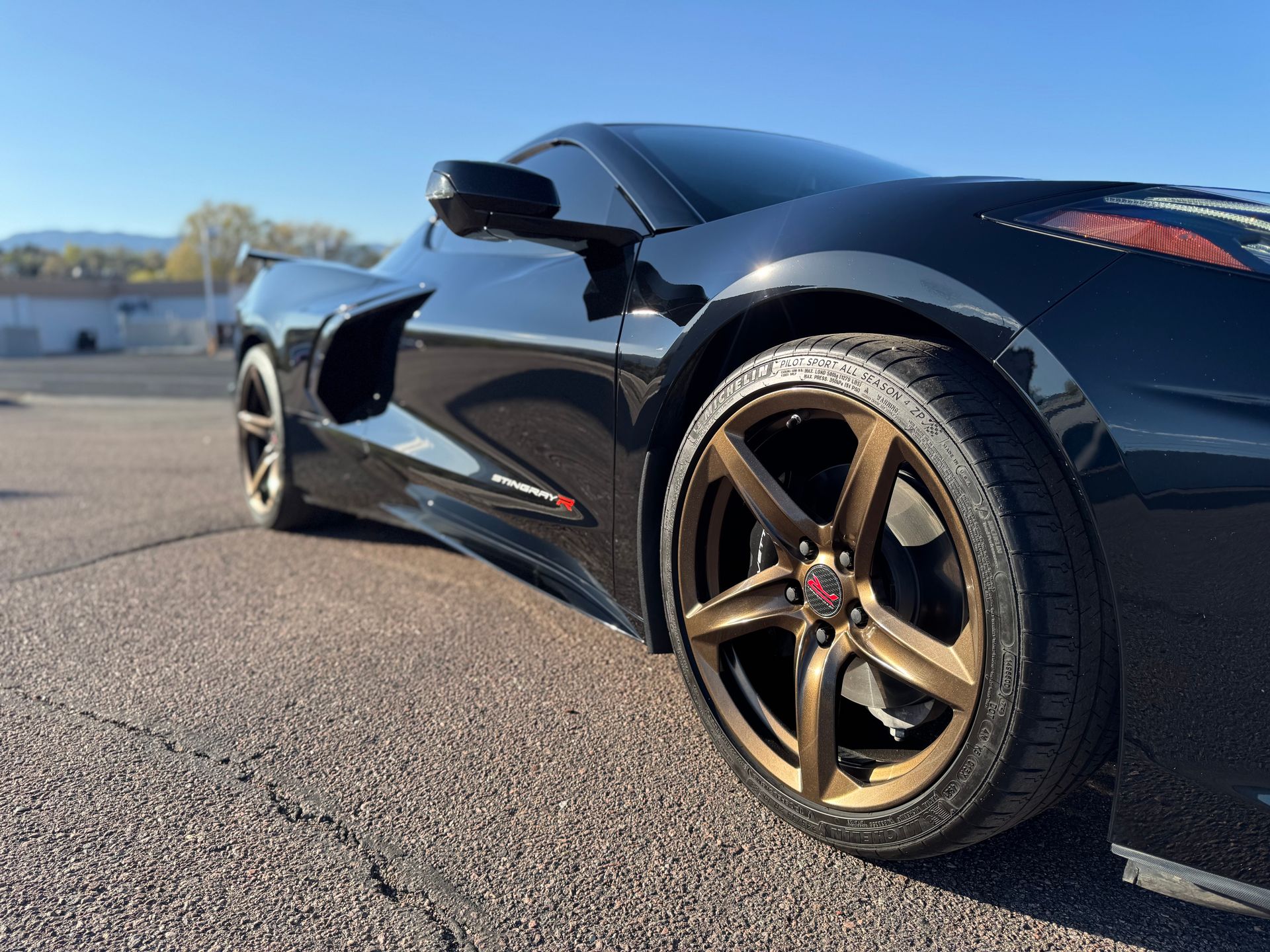 A black sports car with gold wheels is parked on the side of the road.
