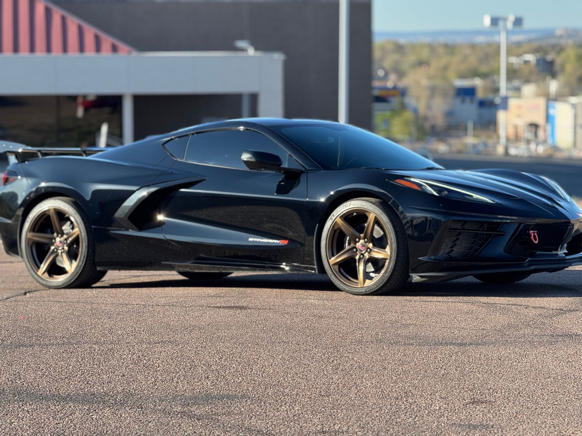 A black sports car is parked on the side of the road in front of a building.