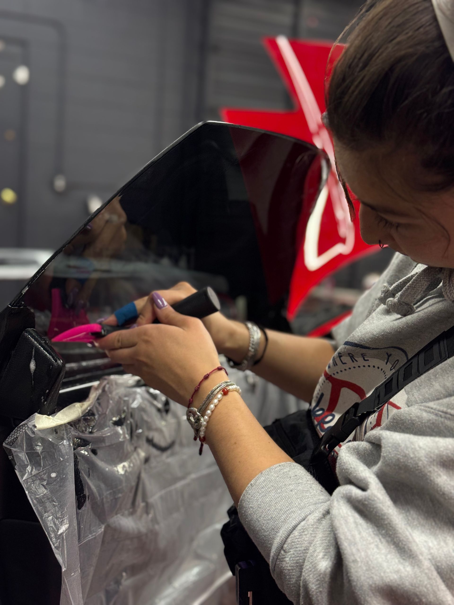 A woman wearing glasses is working on a motorcycle windshield