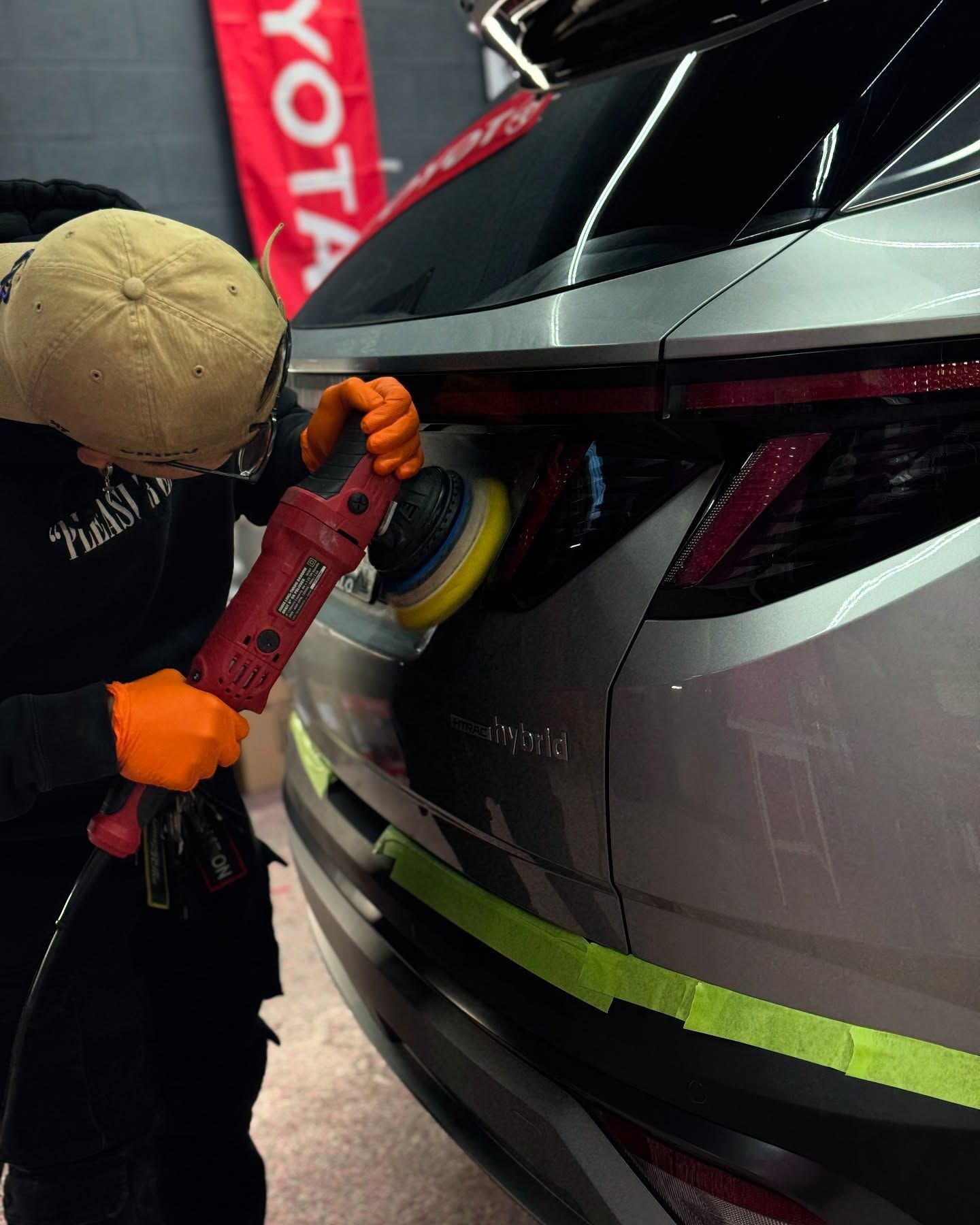 A man is polishing a car with a toyota flag in the background