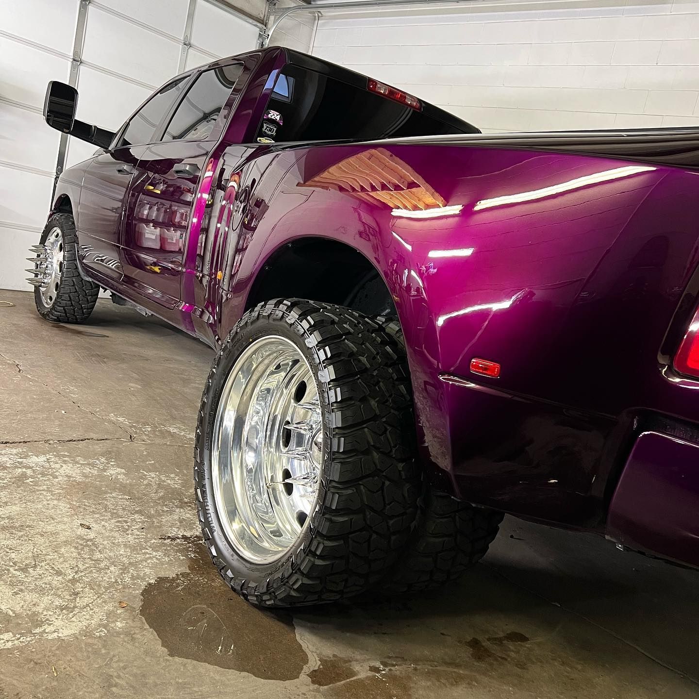A purple truck is parked in a garage next to a garage door.