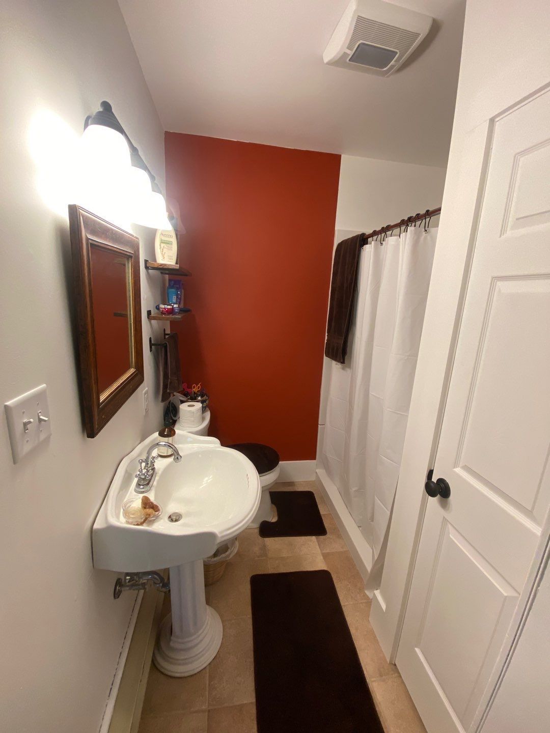 a bathroom with a sink , toilet , mirror and shower curtain