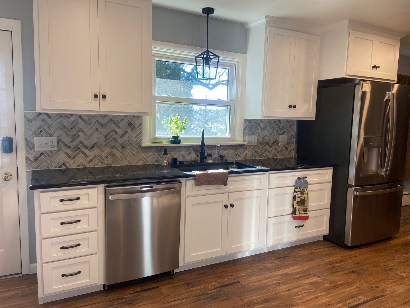 a kitchen with white cabinets, stainless steel appliances, a sink and a refrigerator