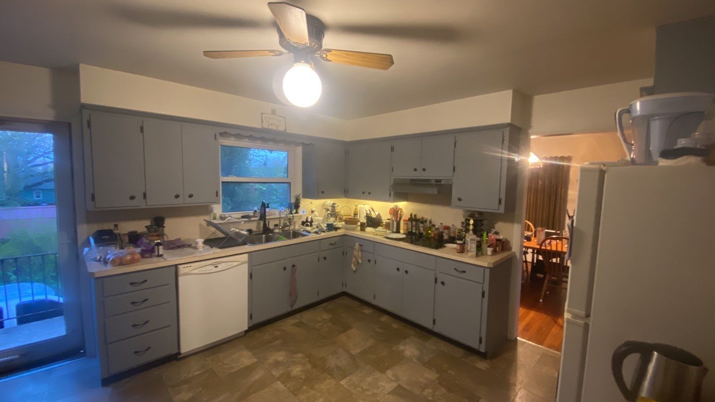 a kitchen with gray cabinets and white appliances and a ceiling fan