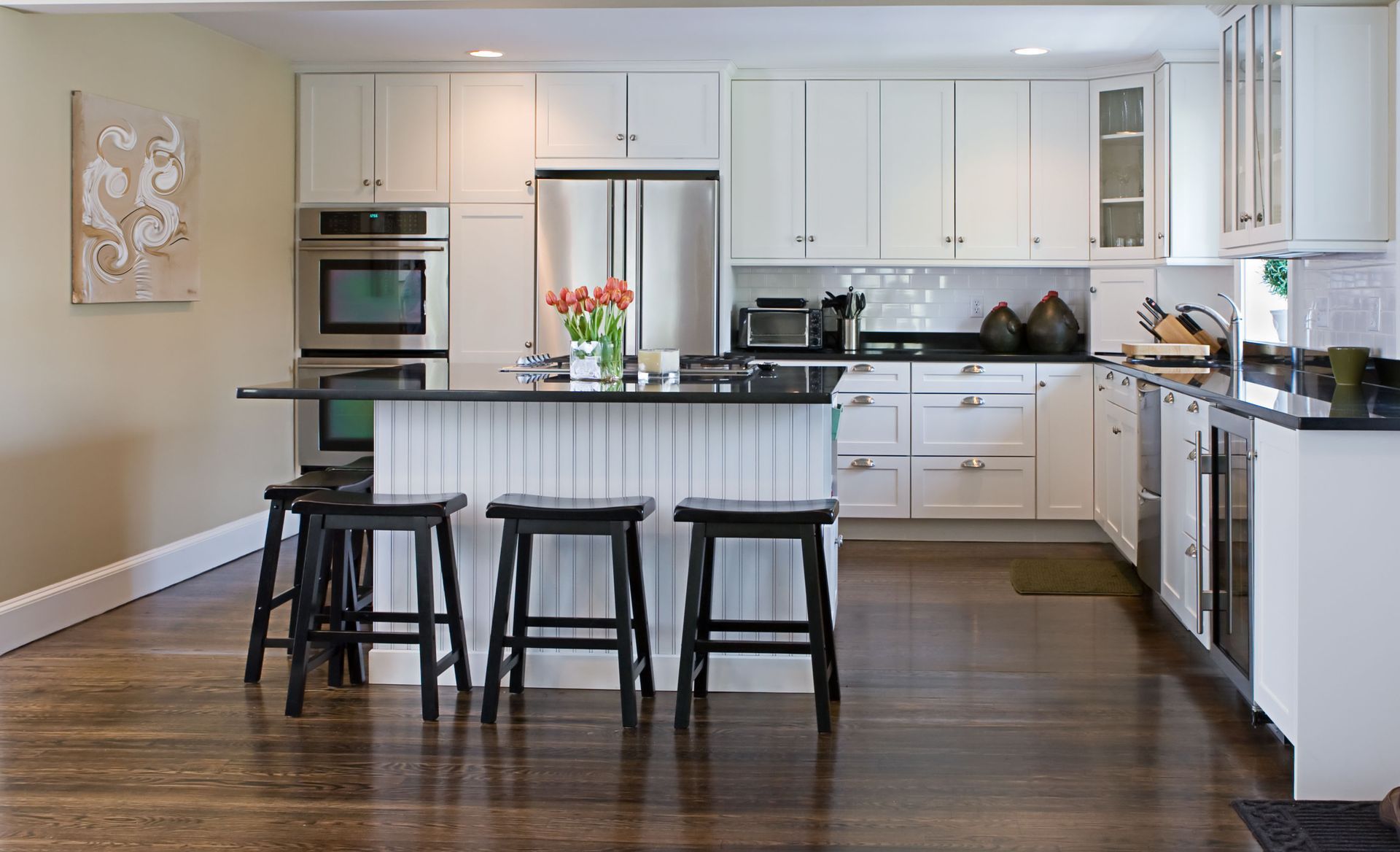 a kitchen with white cabinets and black counter tops