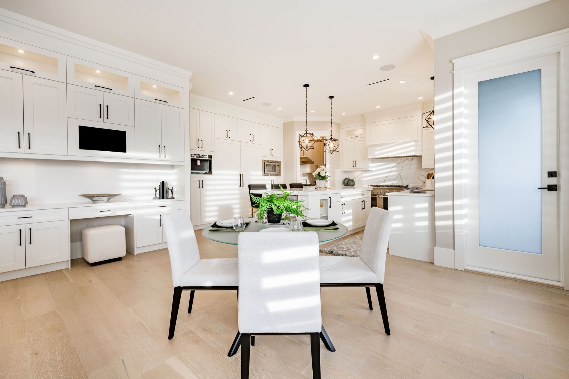 a dining room with a table and chairs and a kitchen in the background