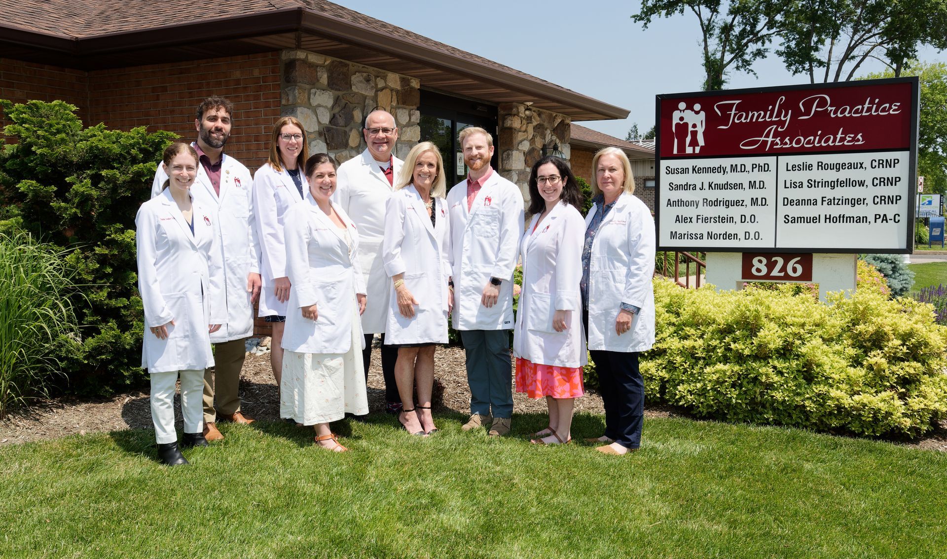A group of doctors are posing for a picture in front of a building.