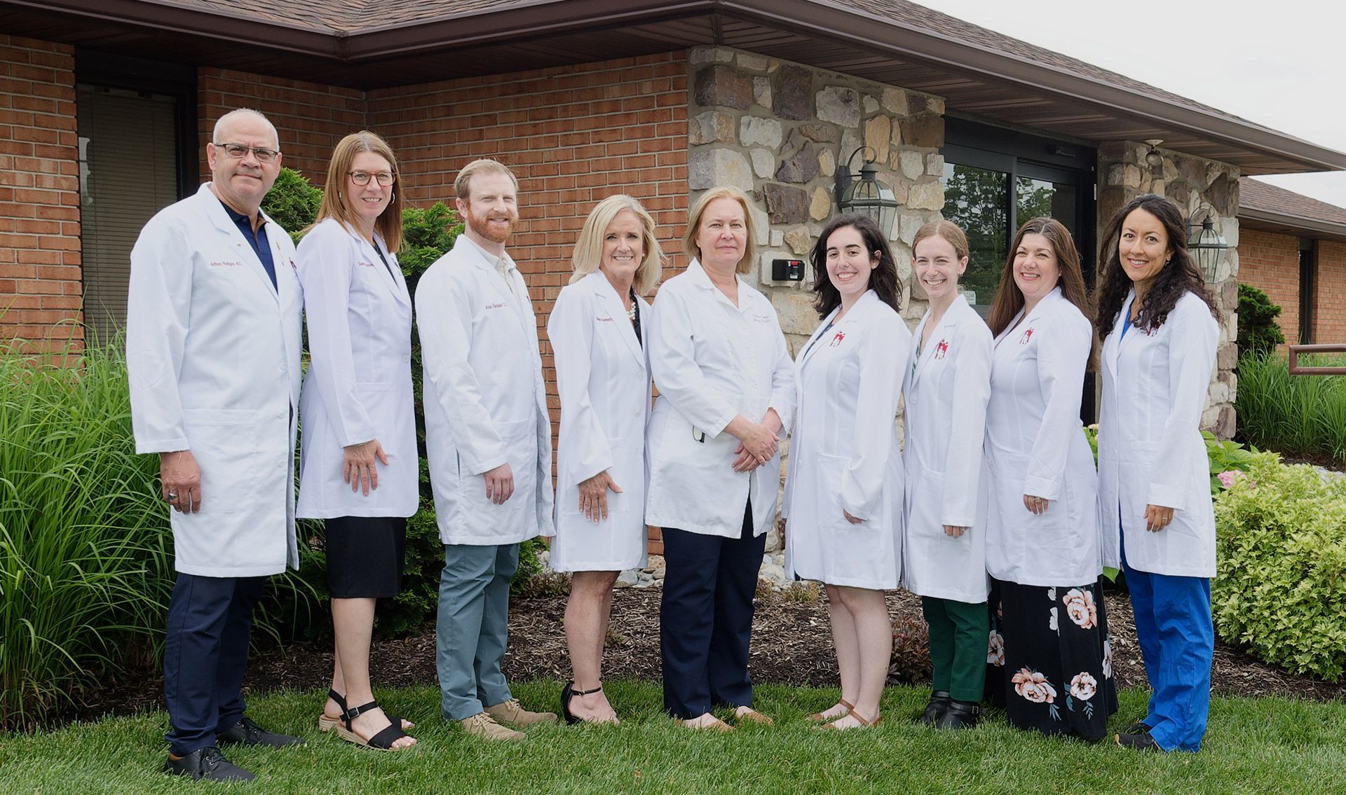 A group of doctors are posing for a picture in front of a building.