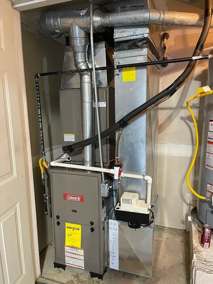Utility closet with furnace, ductwork, and HVAC wiring inside an unfinished basement.