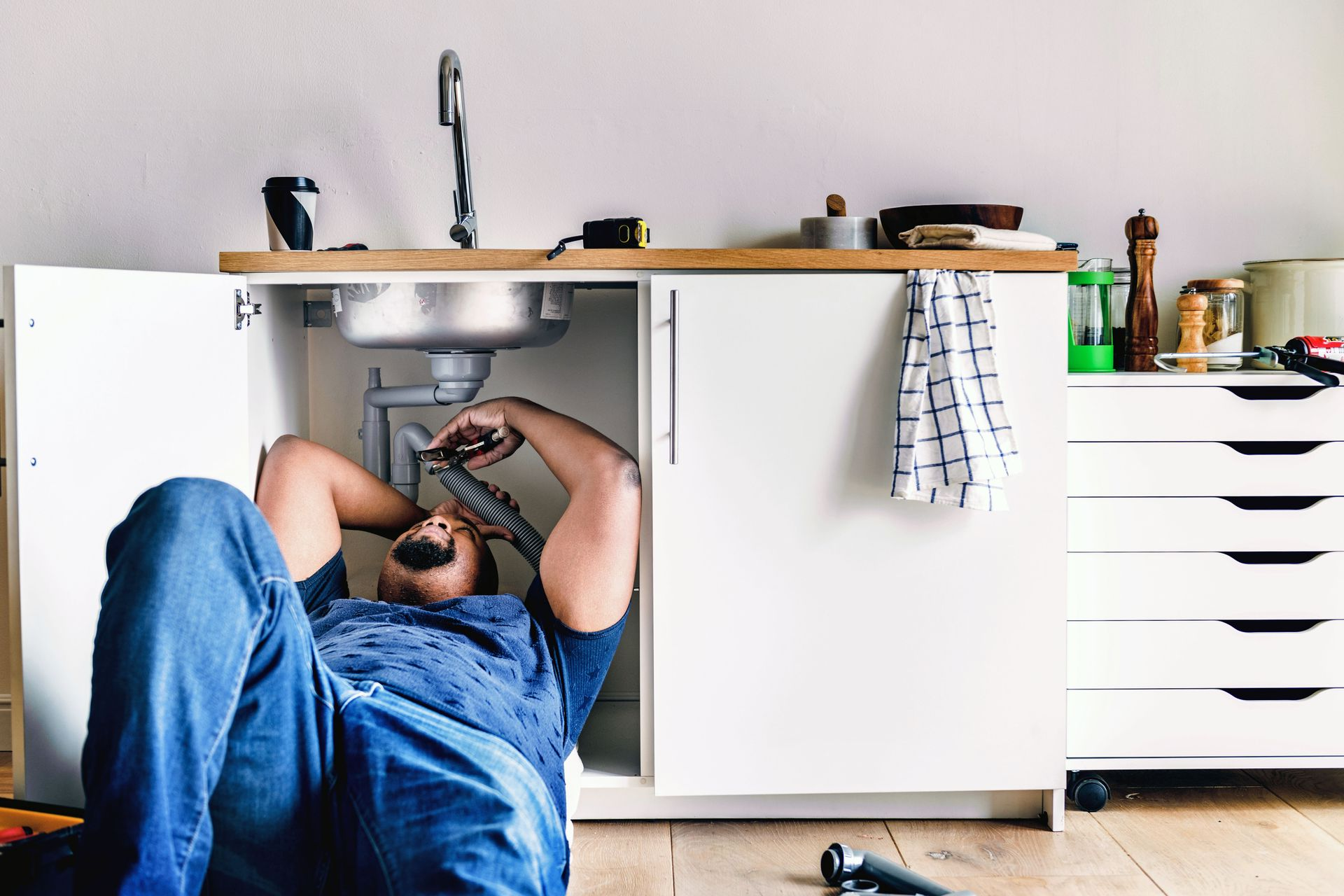 Plumber repairing a bathroom sink drain with a wrench under the basin