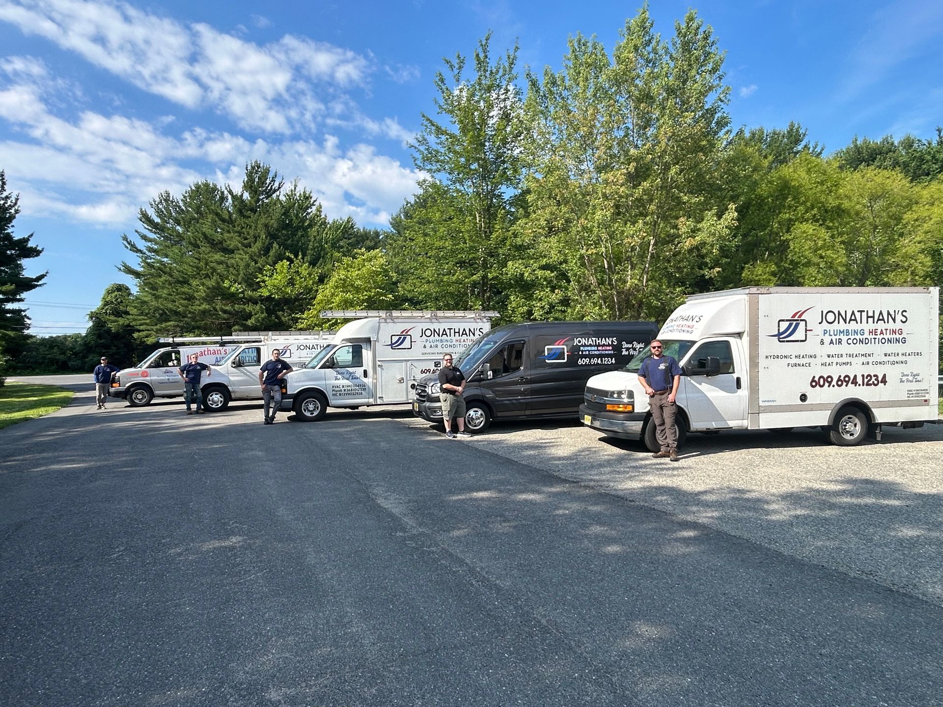 Workers and service vans parked on a gravel lot under a blue sky