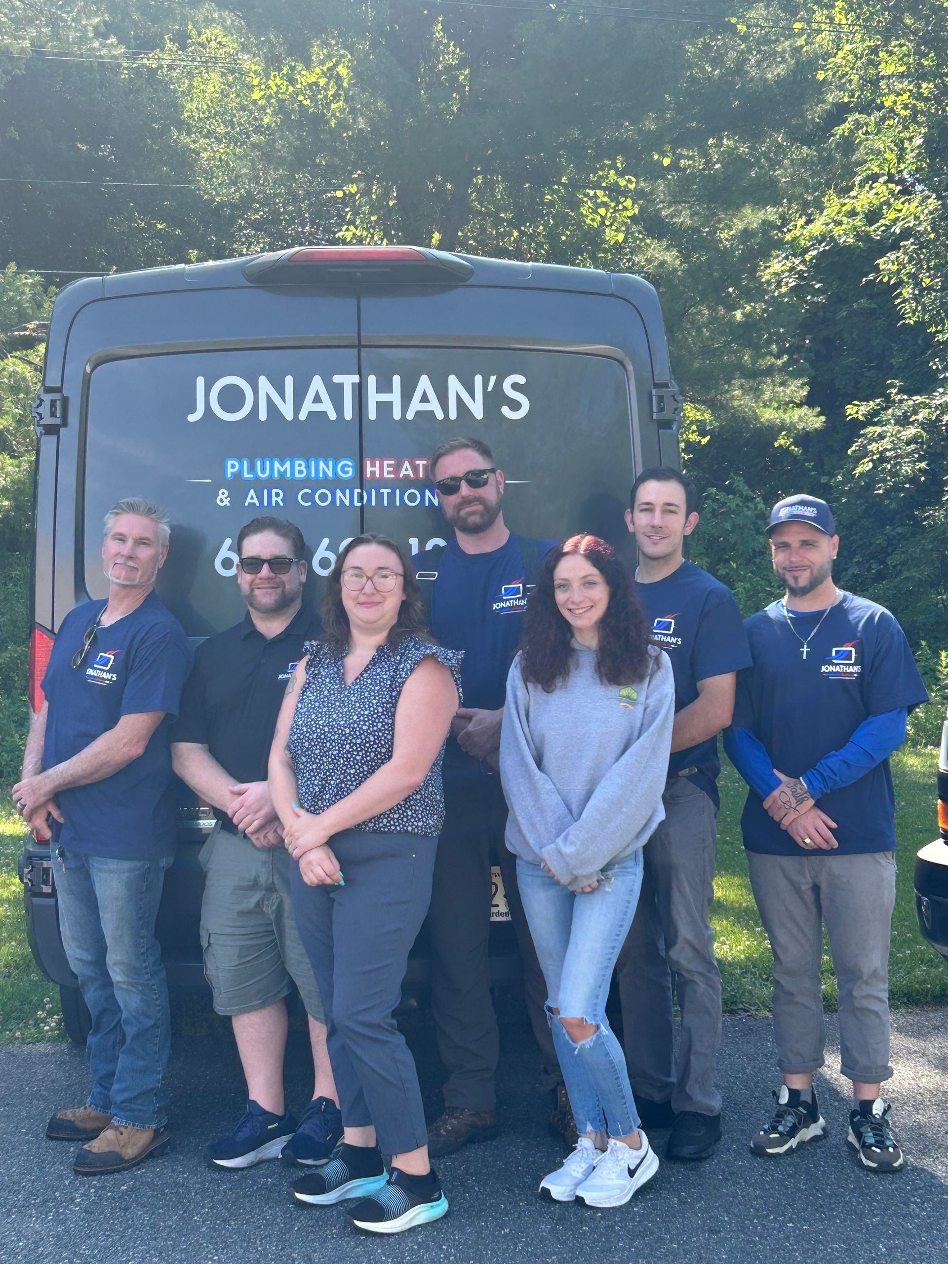 Group of six standing in front of a Jonathan’s food truck outdoors, smiling in sunlight