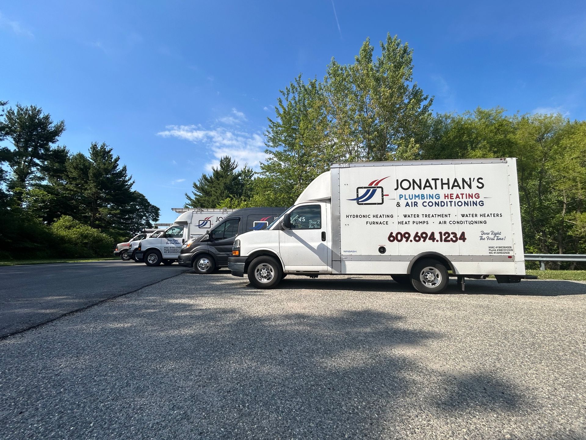 White Jonathan’s service truck parked in a lot beside other vehicles under a blue sky