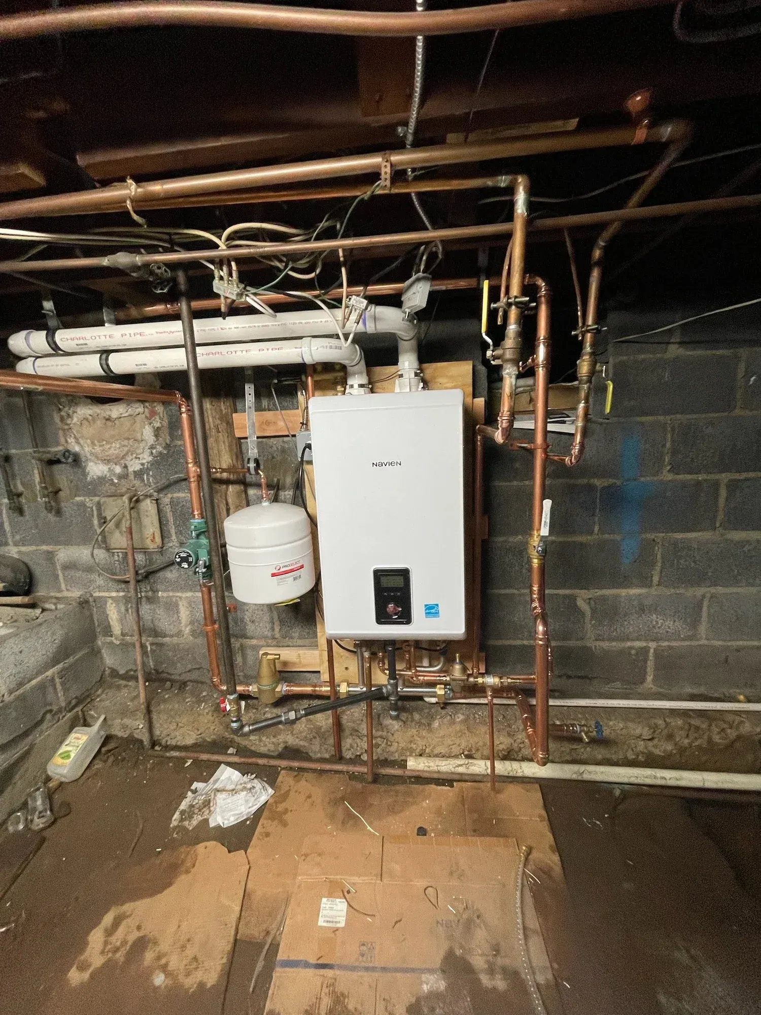 Basement utility room with a wall-mounted boiler, exposed copper pipes, and a water heater tank.