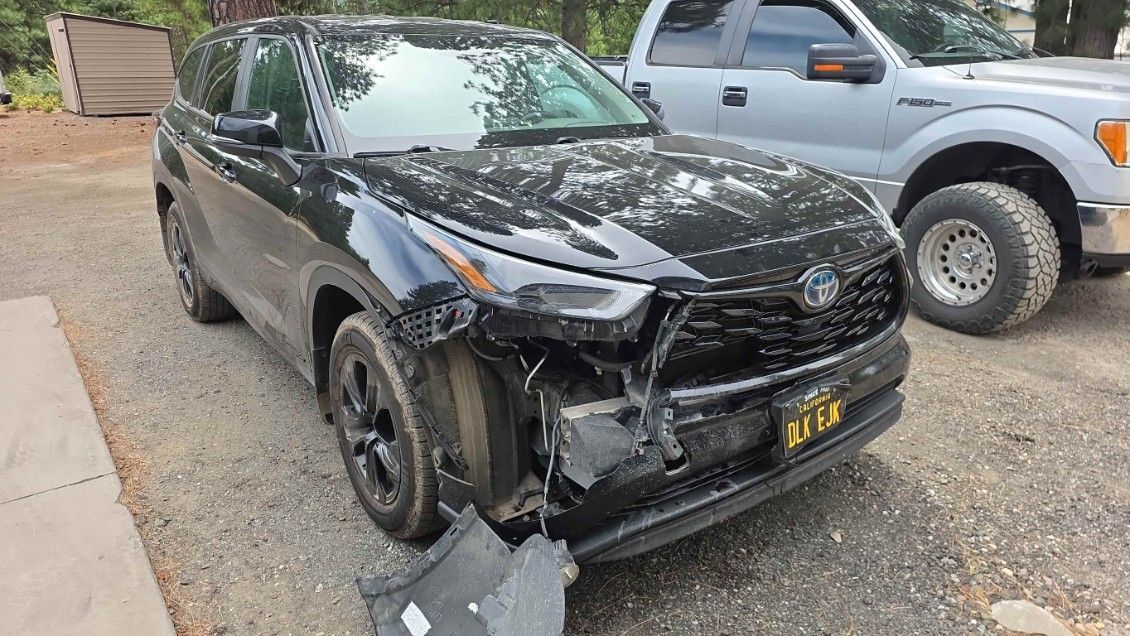 Black SUV with front-end damage parked beside a silver pickup on a gravel lot