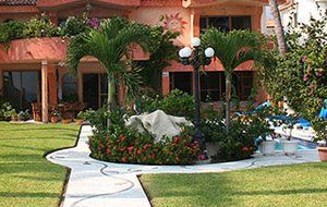 House with green trees and flowers in front of it