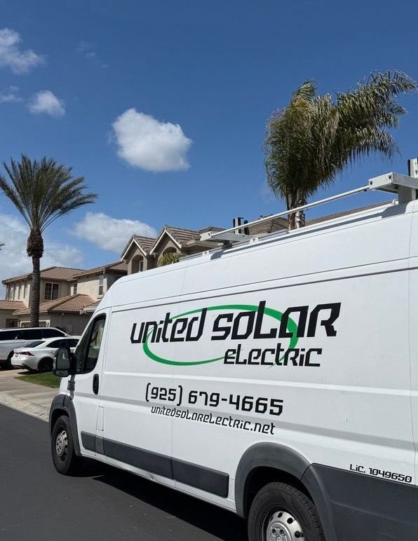 White United Solar Electric van parked on a suburban street under a blue sky with palm trees