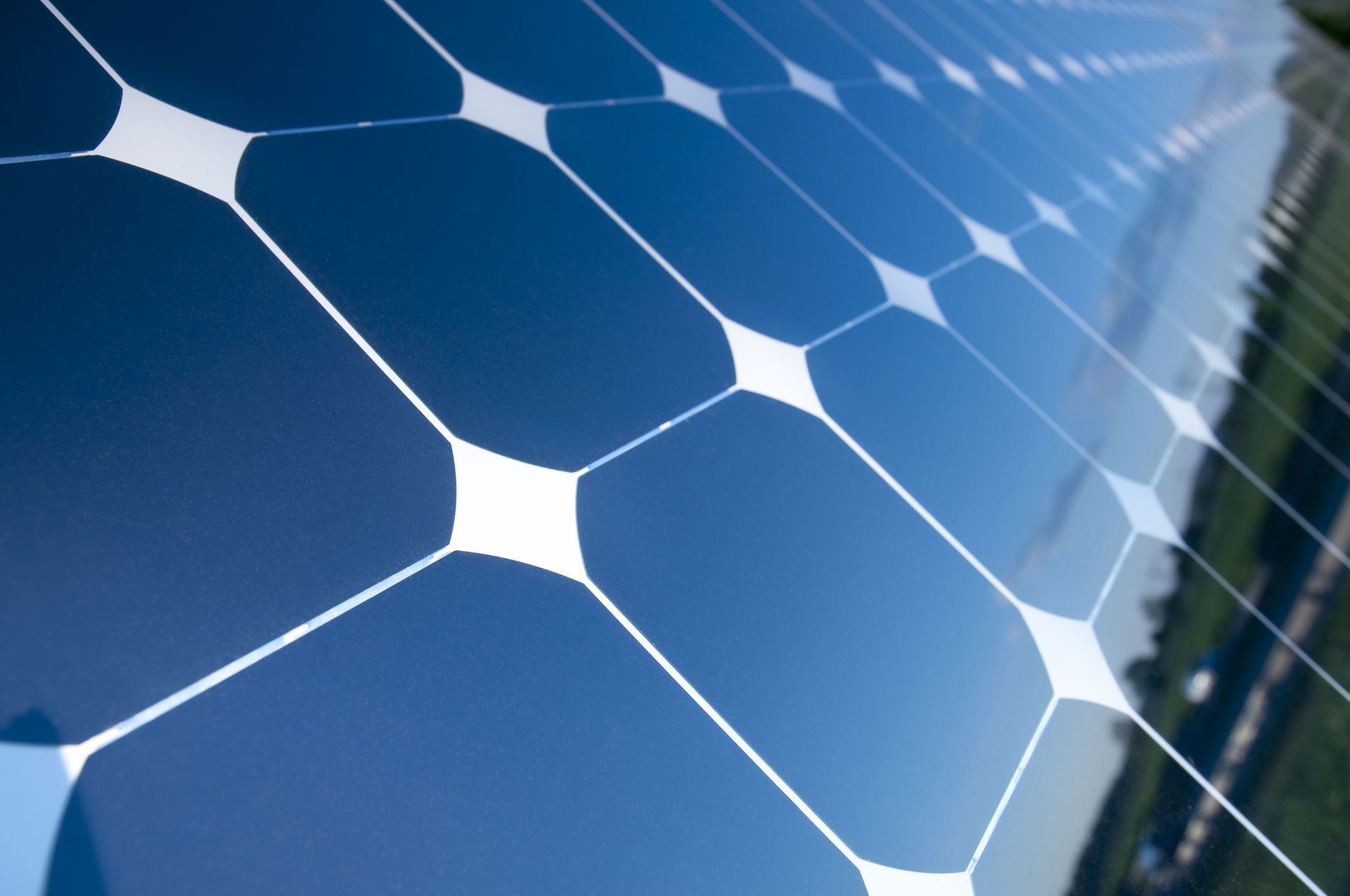 Blue solar panels with white grid pattern reflecting sunlight on a rooftop