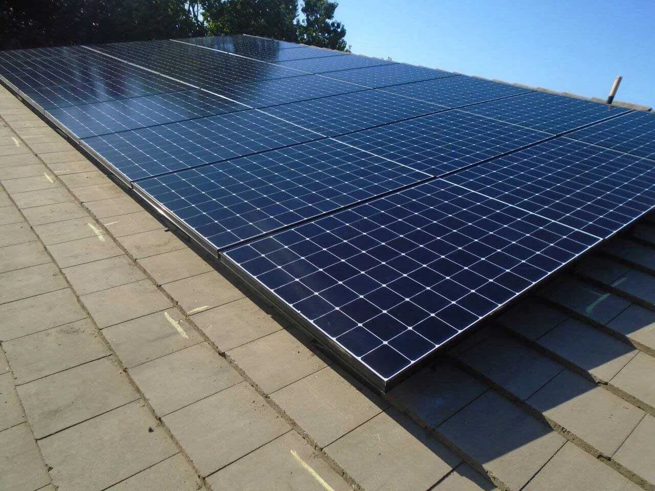 Solar panels installed on a sloped rooftop under a clear blue sky.