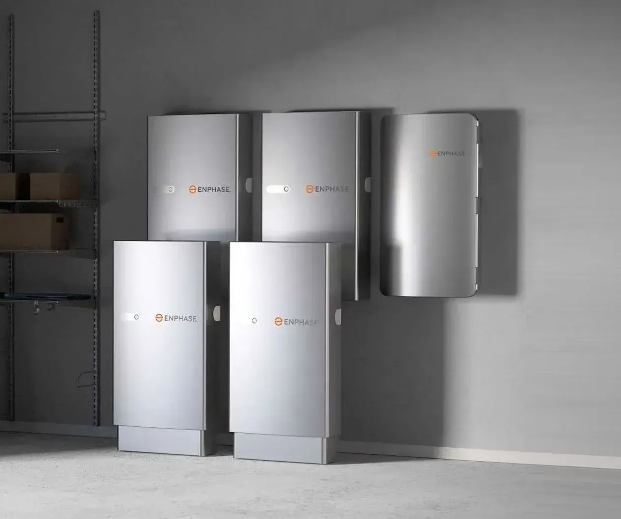 Five silver wall-mounted appliances displayed in a minimalist showroom with a gray wall and floor