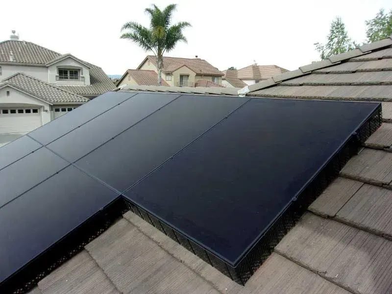 Black solar panels installed on a gray shingle roof in a suburban neighborhood